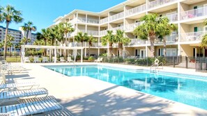 A hotel with a pool, multiple balconies, and palm trees.