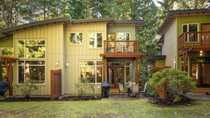 Une maison à deux étages dotée d’une terrasse et d’un patio couvert.
