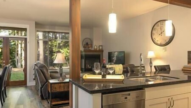 Une cuisine moderne dotée d’un îlot central, d’appareils électroménagers en acier inoxydable et d’un coin repas offrant une vue sur l’extérieur.