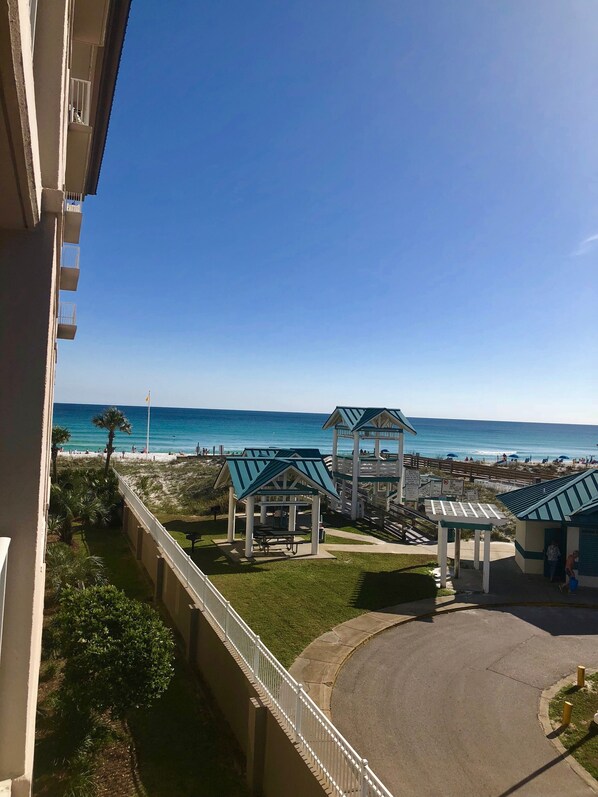 A beach view with a gazebo, a pathway, and a building in the foreground.