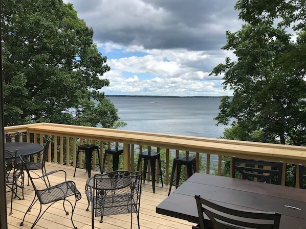 Una terraza de madera con mobiliario exterior con vistas a un lago.