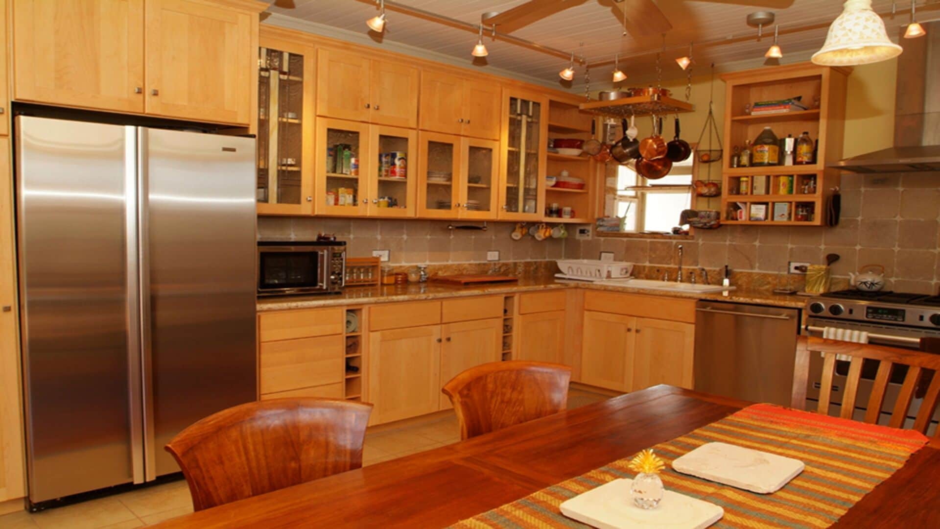 Eine moderne Küche mit Holzausbau, Edelstahlgeräten und einer Essecke mit einem Holztisch und Stühlen.