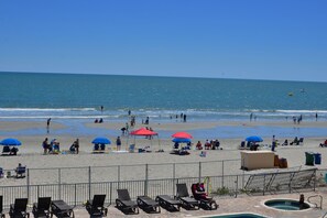 Una playa con tumbonas, sombrillas y una zona de piscina.