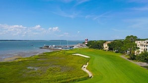 Un parcours de golf situé sur la côte, avec un phare, un port de plaisance et des bâtiments historiques.