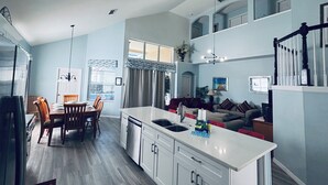 A spacious kitchen with a central island, a dining area with wooden chairs, and a living room with a sofa and a TV. - 6 Bed/Pool/Spa/Internet/gameRoom, 3.5 Miles to Disney,Gated Resort communities (Kissimmee)