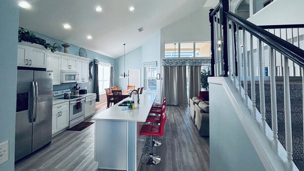 A modern kitchen with a central island, stainless steel appliances, and a dining area with red bar stools. - 6 Bed/Pool/Spa/Internet/gameRoom, 3.5 Miles to Disney,Gated Resort communities (Kissimmee)