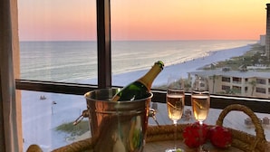 Une table avec une bouteille de champagne, des verres de vin, une assiette de fromage et de crackers, et des étoiles de mer disposées sur un plateau en osier.