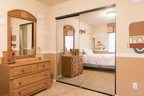 Comfortable bedroom with a large mirror, dresser, and a bed with a white bedspread.