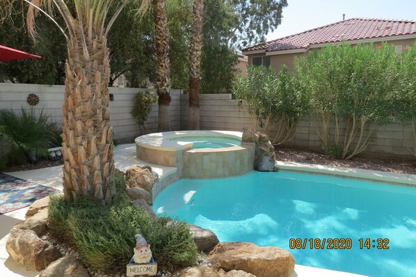 backyard oasis with a swimming pool surrounded by lush landscaping and a small waterfall.