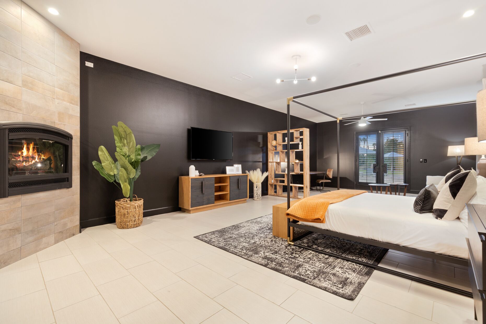 Ein modernes Schlafzimmer mit Kamin, einem großen Bett, einem Fernseher und einer Holzwandregal.