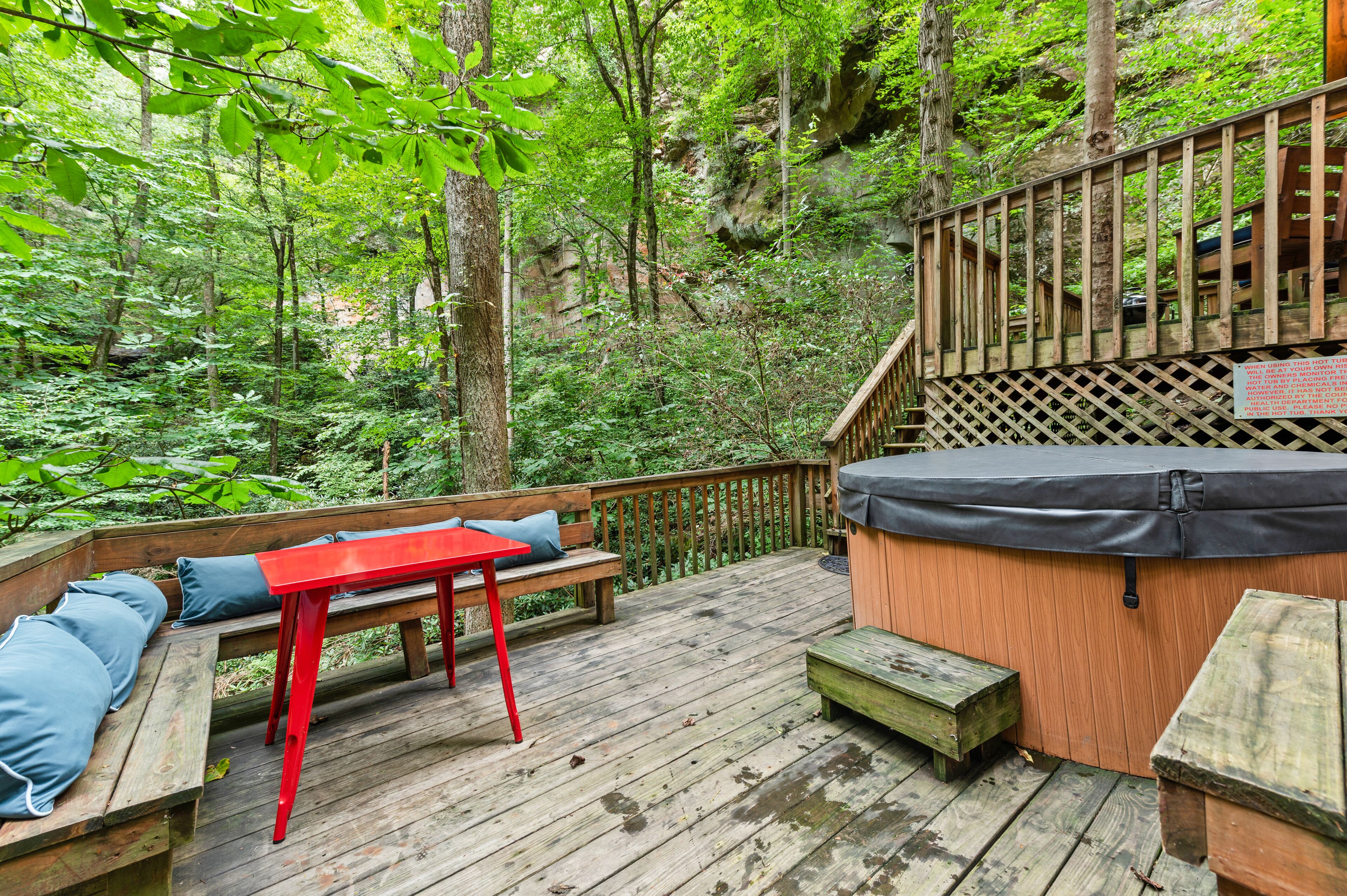 A wooden deck with a hot tub, benches, and a wooden staircase.