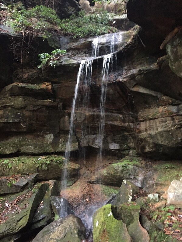 A waterfall cascading over moss-covered rocks in a natural setting.