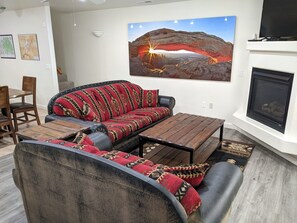 Ein Wohnzimmer mit einem Ecksofa, einem Kamin und einem großen Landschaftsbild an der Wand.