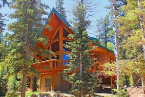 A multi-level log cabin with a prominent balcony, surrounded by dense forest. - Luxury Duck Creek Log Cabin, ATV Trails Access, Near Zion, Bryce, & Brian Head (Duck Creek Village)