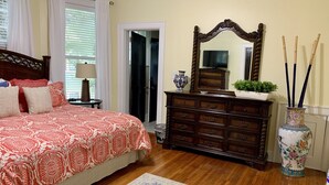 Une chambre à coucher avec un grand lit, une commode en bois, un miroir et des objets décoratifs.