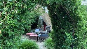A garden pathway leading to a seating area with wicker furniture and a wooden fence. - Bear House 1890, Stinson Suite, Perfect Getaway, Walk to Cafes, Outdoor Activity (Chattanooga)