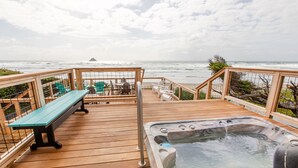 Eine Holzterrasse mit Whirlpool, einer Bank und Sitzgelegenheiten am Meer.