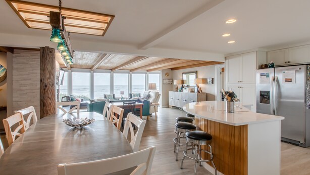 Eine moderne Küche mit einer zentralen Kochinsel, Barhocker und Blick aufs Meer.