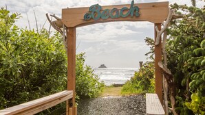 Ein hölzerner Bogen mit dem Schriftzug "Beach", der zu einem Kiesweg führt.