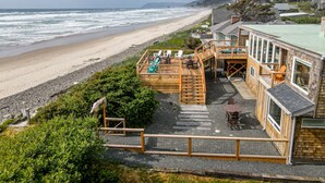 Ein Strandgrundstück mit einer Holzterrasse, Sitzgelegenheiten im Freien und Blick aufs Meer.