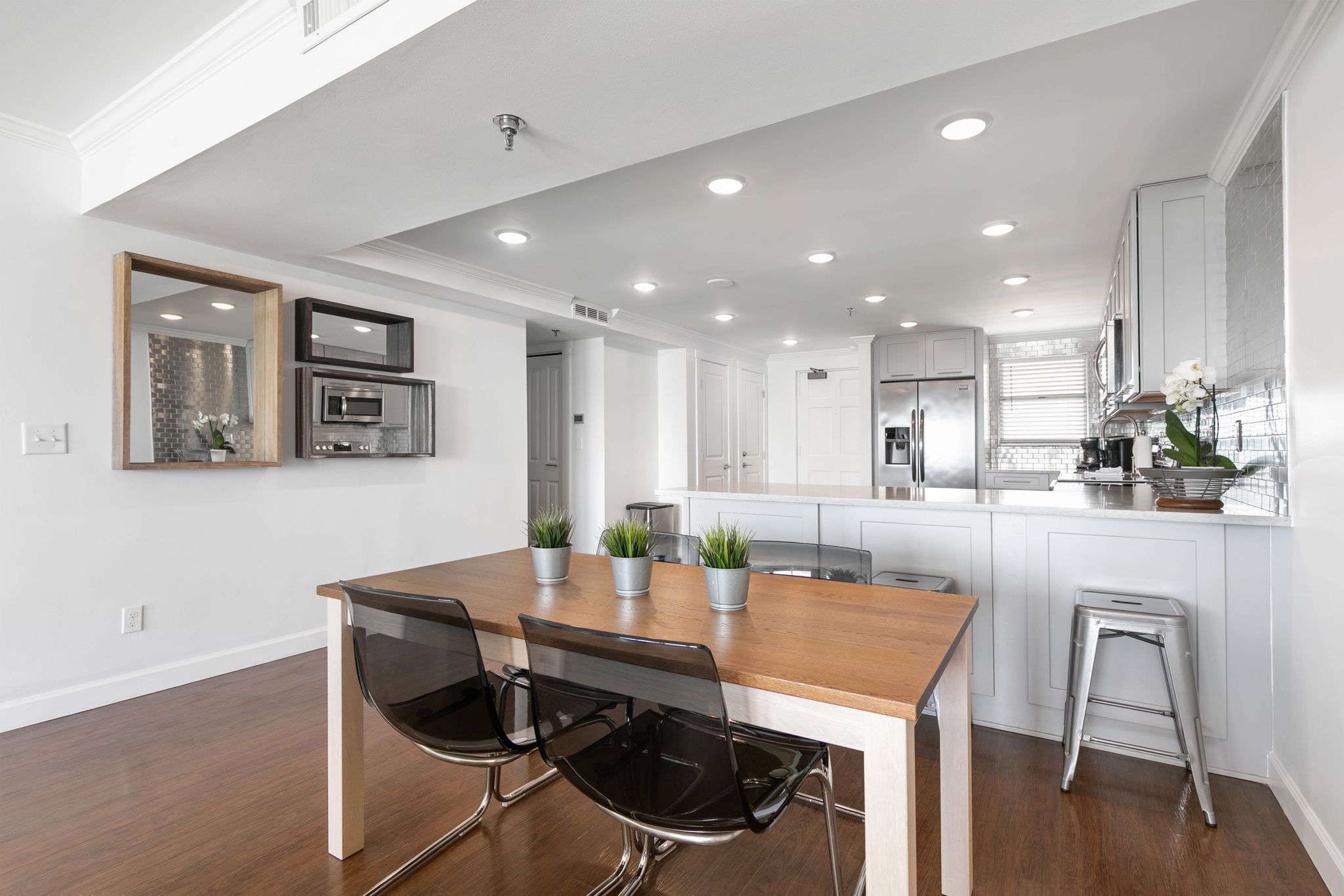 A modern kitchen with white cabinets, stainless steel appliances, and a wooden dining table with chairs.