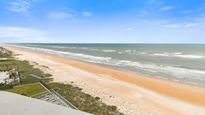 Une vue sur la plage, avec un rivage sablonneux, des vagues et un ciel dégagé.