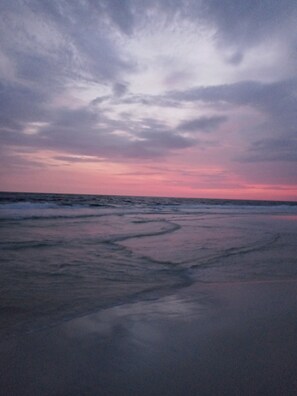 Ein Strand mit ruhiger See und einem Sonnenuntergangshimmel.