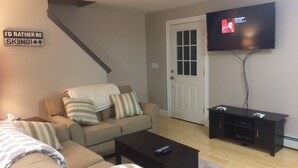 A living room with a sofa, a coffee table, a TV, and a staircase.