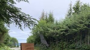 Un panneau en bois portant l’inscription « 3003 HPR », entouré de verdure et bordé par une route.