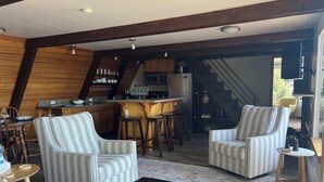 Un salon chaleureux avec des fauteuils à rayures, une table basse et une cuisine en arrière-plan.