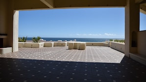 Una terraza al aire libre con vistas al océano, que cuenta con suelo de baldosas y varias zonas de estar.