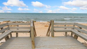 A wooden boardwalk leading to a sandy beach with the ocean in the background.