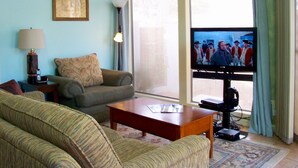 A living room with a sofa, a coffee table, a television, and a lamp.