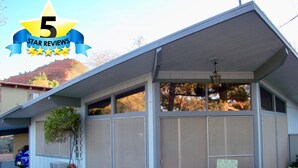 A house with a covered porch, a chair, a table, and a decorative plant.