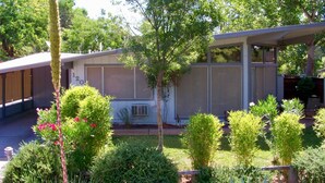 A residential property with a covered patio, a screened-in area, and a variety of landscaped greenery.