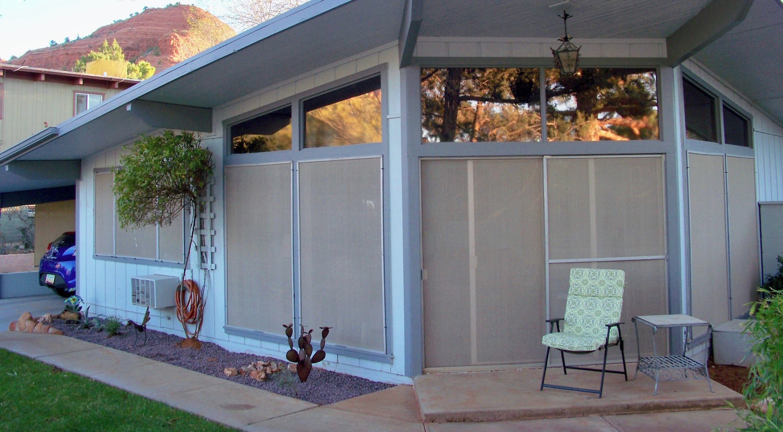 A house with a covered porch, a chair, a table, and a decorative plant.