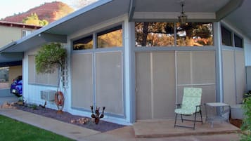 A house with a covered porch, a chair, a table, and a decorative plant.