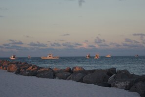 A coastal scene with several boats anchored near a rocky shore. - Beach view condo, serene view of East Pass, walk to beach on Holiday Isle (Destin)