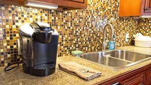 A kitchen with a coffee maker, a sink, and a tiled backsplash.
