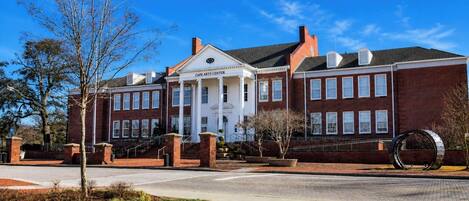 A Cape Arts Center with a symmetrical facade, large windows, and a central entrance with columns.