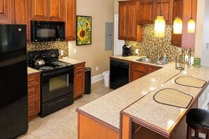 A kitchen with wooden cabinets, a black refrigerator, a microwave, a stove, and a dishwasher.