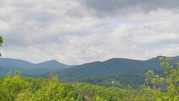 Paisaje montañoso con vegetación densa y cielo nublado.