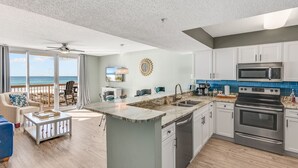 A modern kitchen with a large island, stainless steel appliances, and a view to the outside. - Spectacular Views,  Oceanfront Condo, Renovated (Destin)