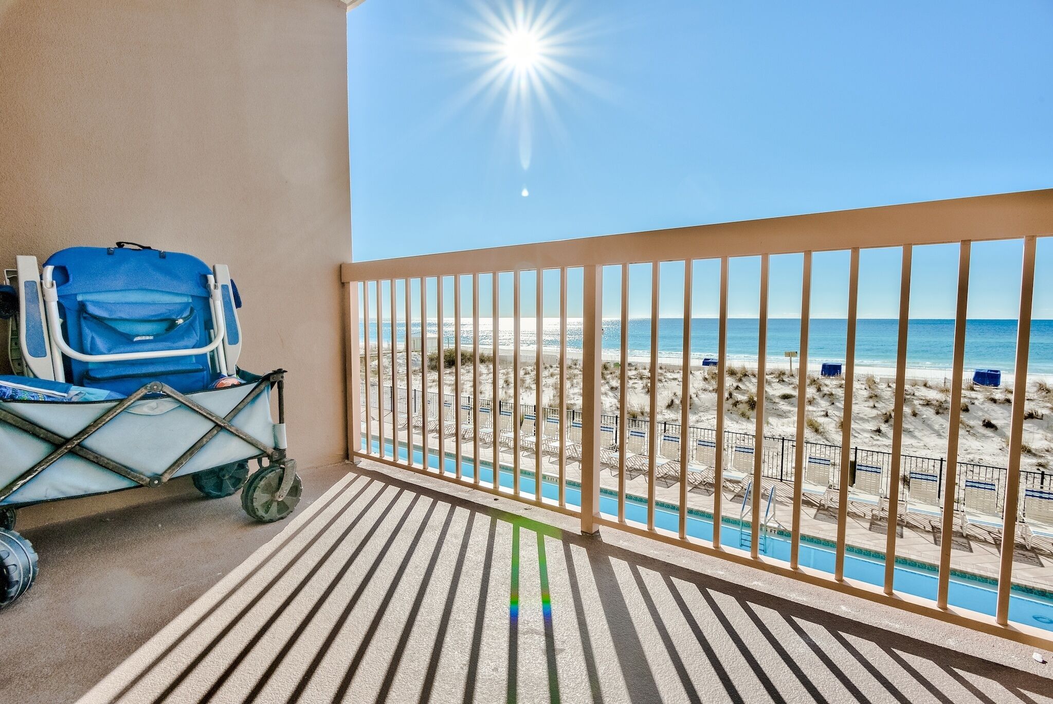 A balcony with a view of a beach and a pool.