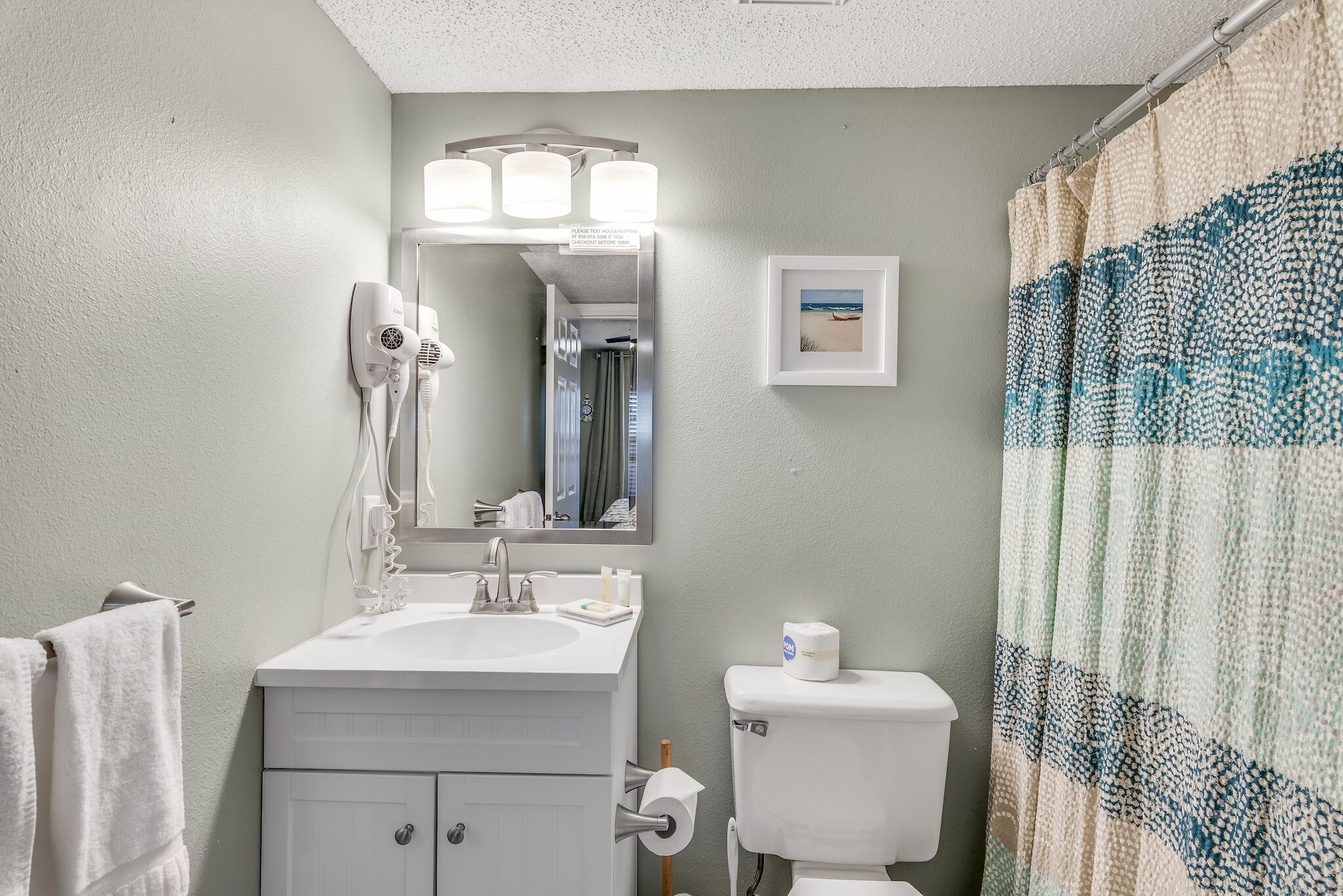 A bathroom with a white sink, a mirror, a toilet, and a shower curtain.