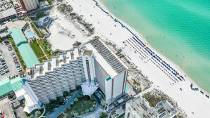 An aerial view of a hotel with a beachfront, including a parking area, a pool, and a beach with umbrellas. - Spectacular Views,  Oceanfront Condo, Renovated (Destin)