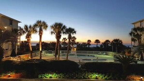 A resort pool area with palm trees and a view of the ocean at sunset. - Beachfront/Oceanfront Hilton Head Island Condo (Hilton Head)