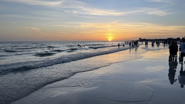 A beach with a sunset, waves, and people walking along the shore. - Beachfront/Oceanfront Hilton Head Island Condo (Hilton Head)