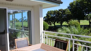 A balcony with a table and chairs, overlooking a golf course and lush greenery. -  A/C, Deluxe, Top Floor, Quiet Development, heated pool, convenient location (Princeville)