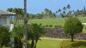 A golf course with a view of the ocean, palm trees, and a building with a balcony. -  A/C, Deluxe, Top Floor, Quiet Development, heated pool, convenient location (Princeville)